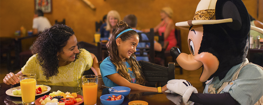 Family enjoying a character breakfast, joined by Mickey Mouse at Tusker House